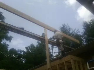 Carpenter setting a ridge beam over a new addition frame — Ice Dam Removal by Roofing Brothers in Barnard