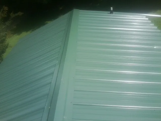 New green metal panels meeting at the ridge of a roof — Flat Roof Repair work by our crew in Barnard