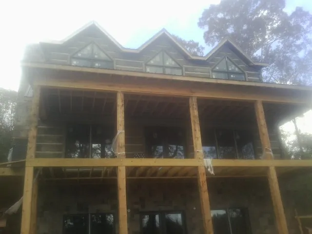 Dormers and porch framing on a large log home under construction — Roof Coating work by our crew in Barnard