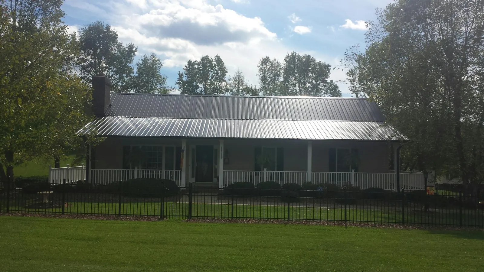 Gray metal roof on a brick ranch with a full width front porch — Gutter Guard Installation work by our crew in Barnard