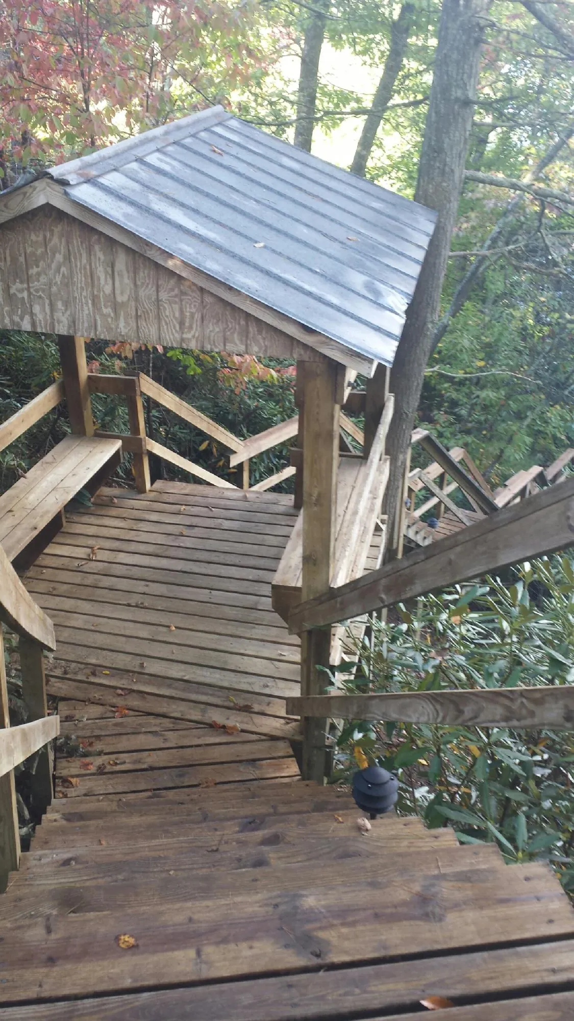 Metal roofed shelter over wooden steps on a wooded walkway — Skylight Repair & Installation work by our crew in Barnard