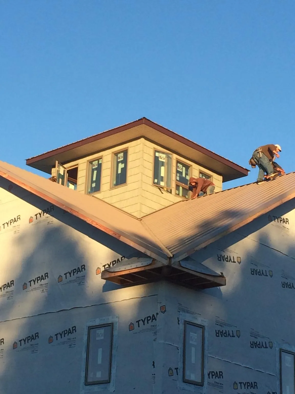 Roofers working around a rooftop cupola on a new metal roof at sunset — Roof Waterproofing in Barnard by Roofing Brothers